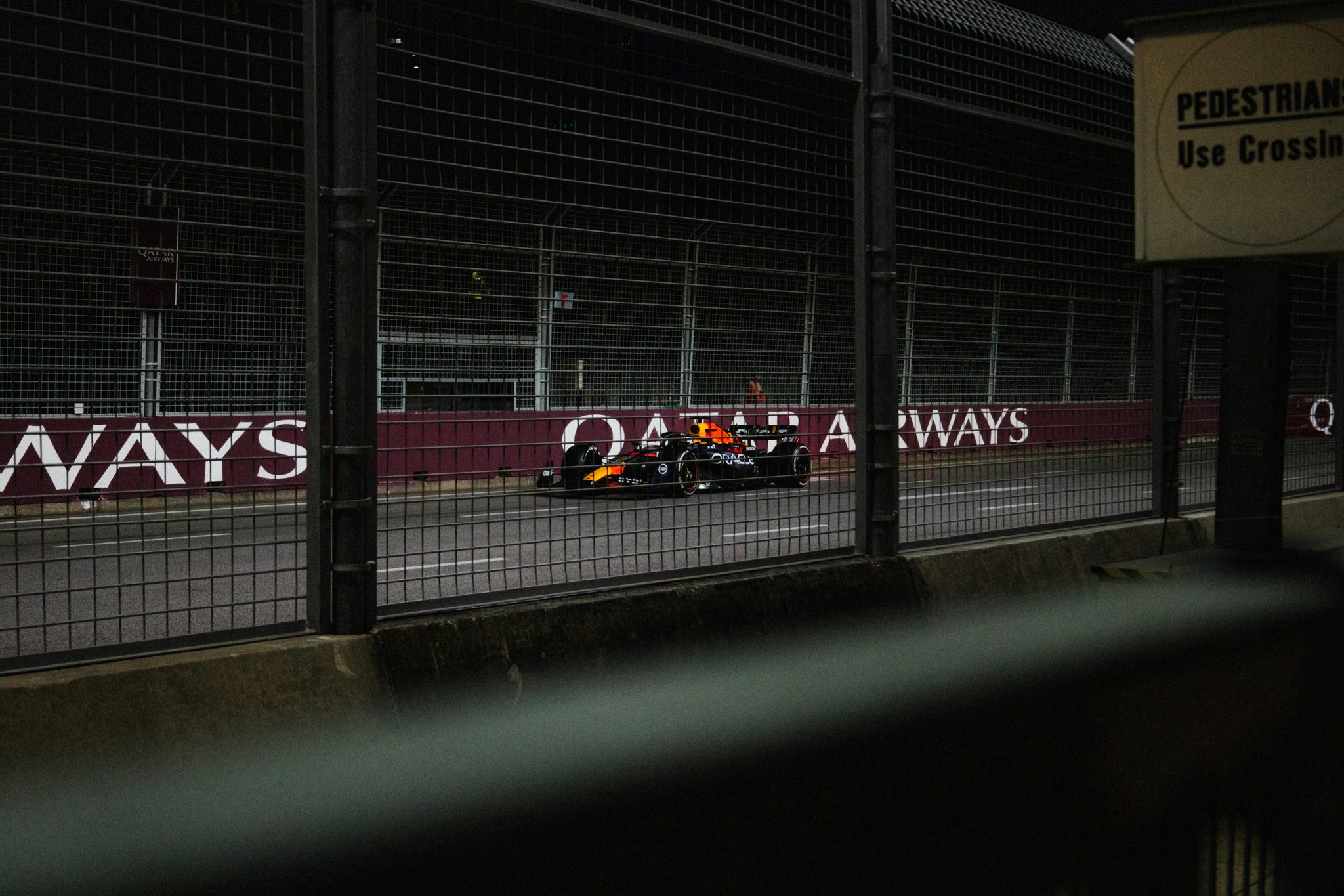Een Formule 1-auto op het circuit, gezien door het hek